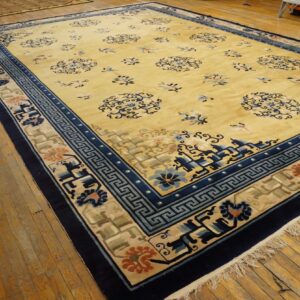 Large yellow rug with dark blue borders and stylized floral medallions on distressed wooden plank flooring.