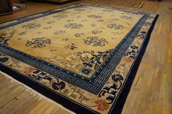 Golden yellow rug featuring scattered blue floral motifs and wide geometric navy and beige borders on wood flooring.
