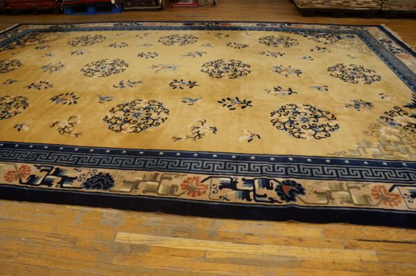 Large golden yellow rug featuring scattered blue floral motifs and multi-color borders on wood planks.
