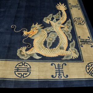 Navy blue rug with a large golden dragon corner motif and a wide tan border featuring geometric symbols.