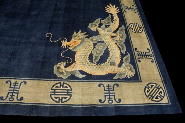 Navy blue rug with a large golden dragon corner motif and a wide tan border featuring geometric symbols.