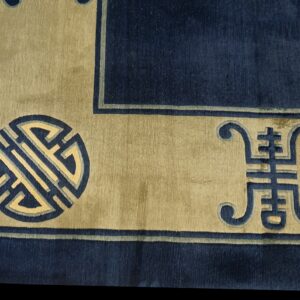 A plush navy rug border with a tan band featuring traditional blue and cream geometric and symbolic motifs.