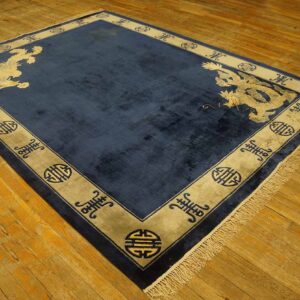Navy blue rug featuring pale animal motifs and a wide beige border on rustic wooden flooring.