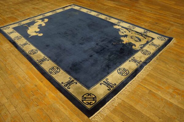 Navy blue rug featuring pale animal motifs and a wide beige border on rustic wooden flooring.