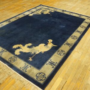 Blue area rug with light yellow dragon and phoenix designs and a patterned border on a wood plank floor.