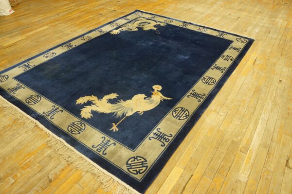 Blue area rug with light yellow dragon and phoenix designs and a patterned border on a wood plank floor.