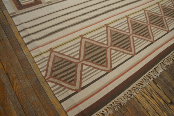 Geometric flatweave rug in neutral browns, ivory, and terracotta stripes, resting on distressed hardwood.