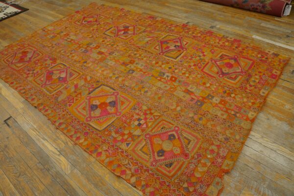 Geometric orange, yellow, and fuchsia rug with a complex, low-texture pattern sits on light wood flooring.