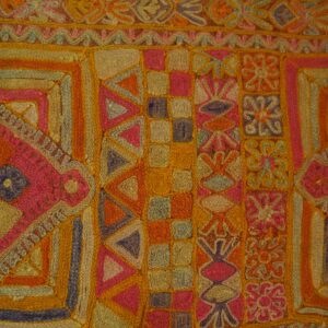 Highly textured rug with bands of pink, orange, and gold geometric motifs resting on wood floorboards.
