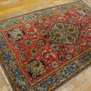 Low-pile rug in red, blue, and green featuring dense floral and animal designs rests on rustic hardwood.