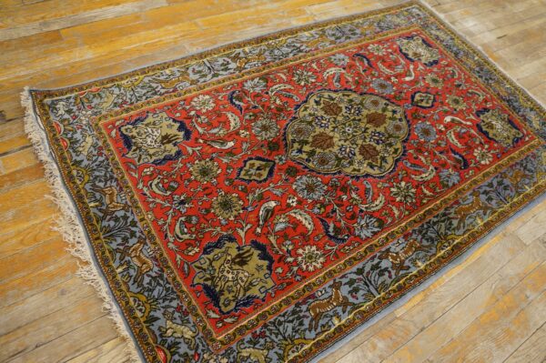 Low-pile rug in red, blue, and green featuring dense floral and animal designs rests on rustic hardwood.