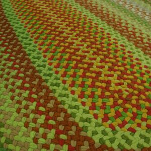 A high-textured, braided rug features diagonal bands of green, brown, red, and gold colors.