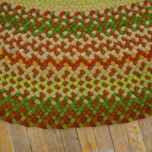 Braided rug featuring thick stripes of green, rust, beige, red, and yellow on distressed wooden floorboards.