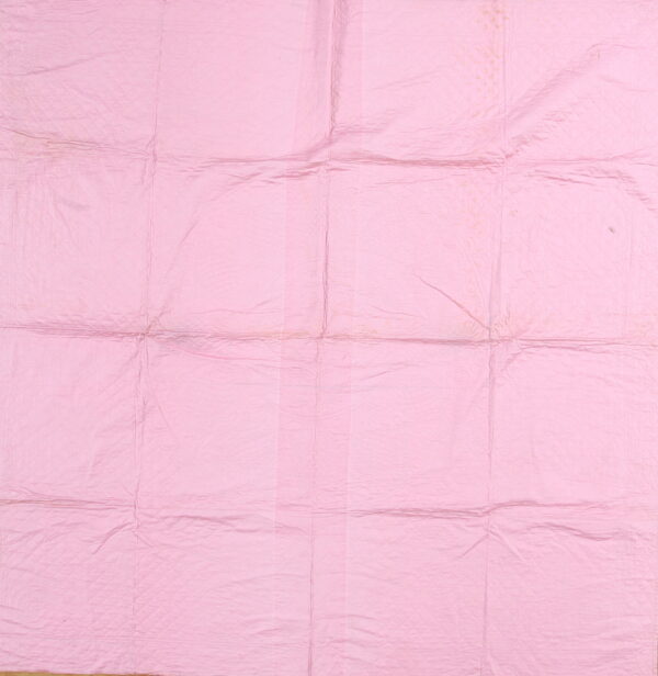 Light pink, heavily creased textile showing a quilted diamond pattern and prominent folds across the surface.