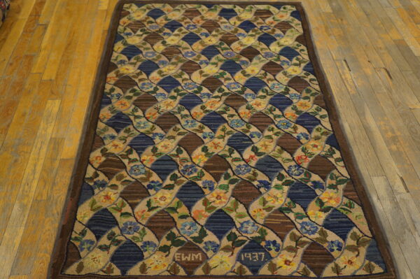 A high-texture rug featuring an interlocking floral lattice pattern in brown, blue, and tan on wood flooring.