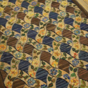 Multi-colored runner featuring a wavy floral lattice over alternating dark blue and striped brown panels on a wood floor.