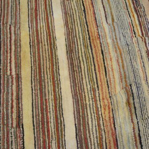 Close up of a multicolored textured rug featuring vertical stripes in mixed, muted colors.