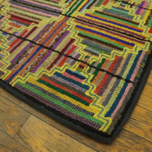 Multicolored rug with striped rectangular blocks and bright yellow borders lying on rustic wood floor.