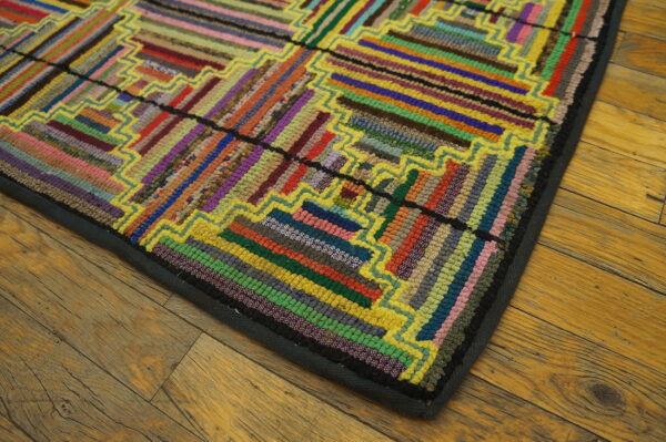 Multicolored rug with striped rectangular blocks and bright yellow borders lying on rustic wood floor.