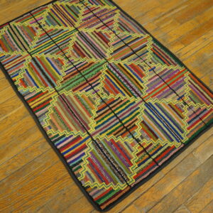 A vividly multicolored rag rug featuring a segmented log cabin quilt design rests on aged hardwood floors.