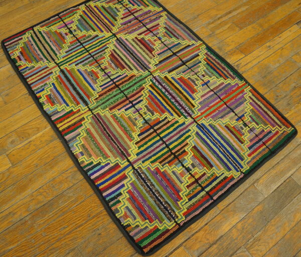 A vividly multicolored rag rug featuring a segmented log cabin quilt design rests on aged hardwood floors.