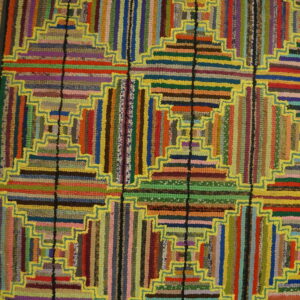 Multicolor textured rug featuring stepped geometric log cabin blocks outlined in bright yellow on a wood floor.