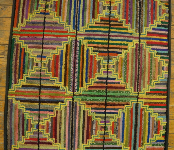 Multicolor textured rug featuring stepped geometric log cabin blocks outlined in bright yellow on a wood floor.