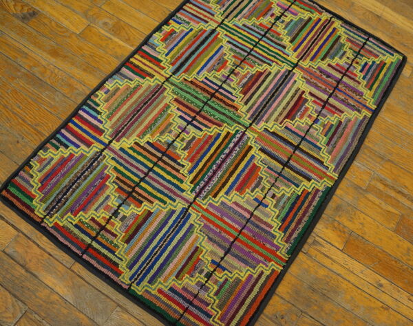 Rectangular low-pile rug featuring a vibrant, striped geometric pattern with yellow outlining on wood planks.