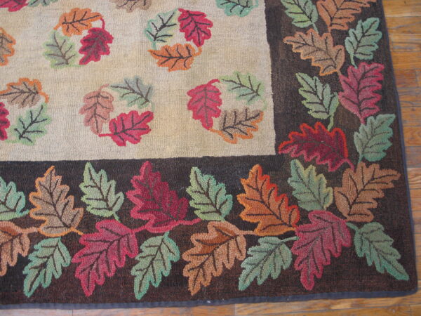 Textured rug displaying multicolored fall leaves on a light field and a dense, dark brown leafy border.