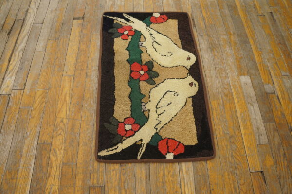 Coarse looped rug featuring a design of two white birds and red flowers on worn wooden planks.