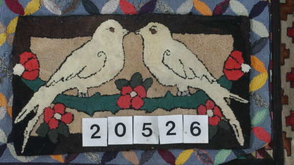 Low-pile hooked rug displaying two cream birds, red flowers, and a brown and tan background.