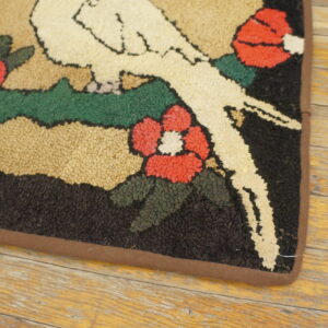 Highly textured rug with white birds, red flowers, and green leaves resting on worn wood flooring.