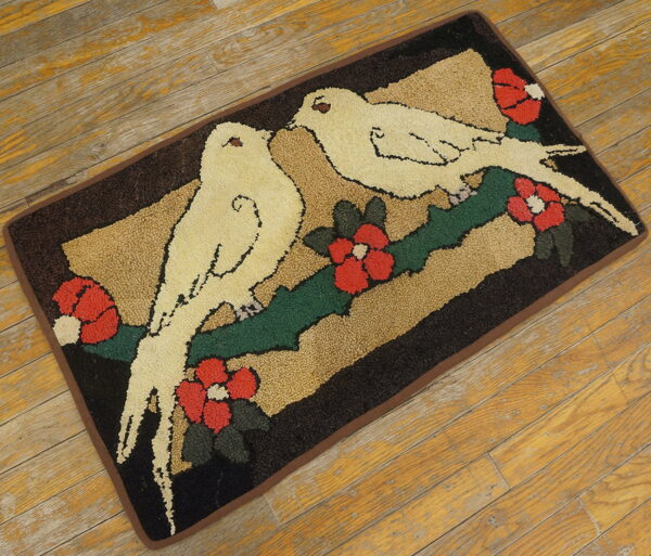 Textured rug with cream birds, red flowers, and green leaves on a dark brown and tan background on wood.