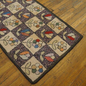 Chunky hooked runner featuring cream and multi-color floral diamond motifs rests on rustic wood planks.