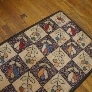 Multicolor textured rug featuring a botanical diamond pattern with tan and speckled navy sections on hardwood flooring.