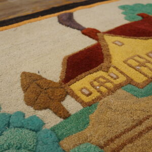 Close-up of a textured rug displaying a yellow house, red roof, and green foliage against a beige background.
