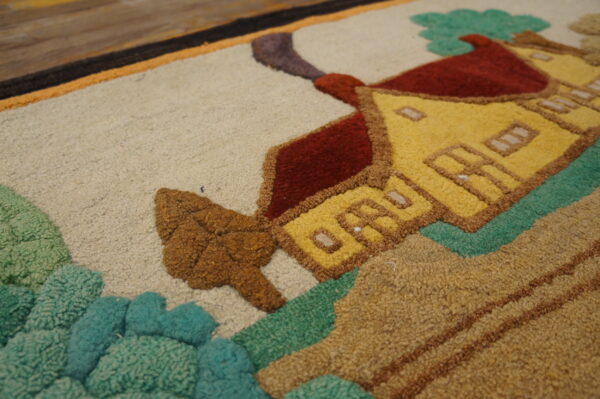 Close-up of a textured rug displaying a yellow house, red roof, and green foliage against a beige background.