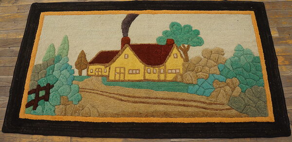 Hooked rug featuring a bright yellow cottage, green trees, and brown landscape, framed by thick dark borders.