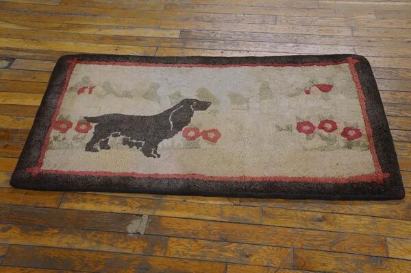 A rectangular mat featuring a dark dog motif and red flowers on a beige ground, bordered in brown, rests on wood planks.