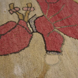 Textured looped rug closeup featuring large magenta leaves and flowers on a creamy white field.