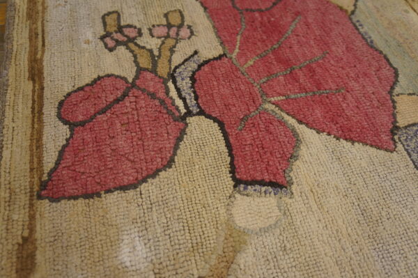 Textured looped rug closeup featuring large magenta leaves and flowers on a creamy white field.