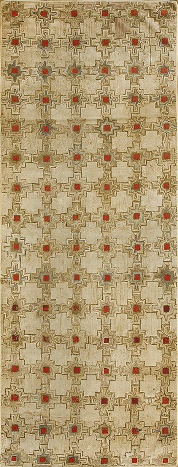 Textured beige rug with a repeating geometric pattern of red squares and intricate brown and gray outlines.