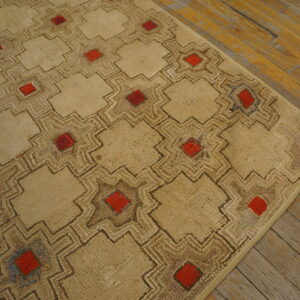 Textured beige rug with an interlocking geometric pattern, red squares, and exposed plank wood flooring.