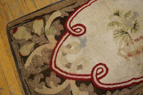 Textured rug featuring red-bordered cream medallion and brown foliate design on distressed wooden flooring.