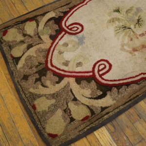 Cream, brown, and red rug with a prominent floral pattern and looped texture on distressed wood plank flooring.