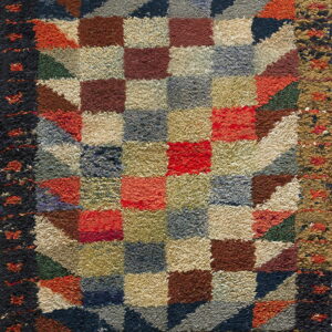 Shaggy, multicolored rug with a central square checkerboard pattern and geometric block borders.