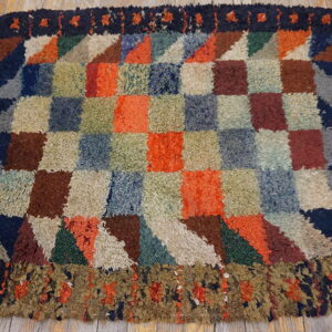 Multicolored patchwork rug with thick, shaggy pile and block design resting on light wood flooring.