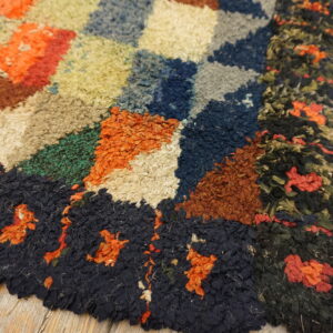 High-pile abstract rug showing colorful geometric blocks and a dark border on rustic wooden planks.
