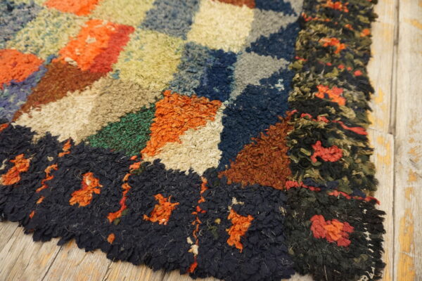 High-pile abstract rug showing colorful geometric blocks and a dark border on rustic wooden planks.