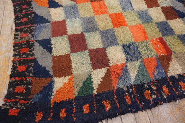 A colorful, high-pile rug with a checkerboard and geometric pattern rests on rustic wood flooring.